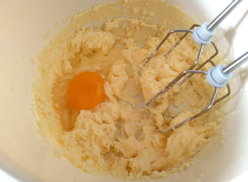 1. Этап. Пирожные Ламингтон, ароматизированные цедрой апельсина: Взбейте размягчённое масло (120 г) с сахаром (75 г) в пышный крем, а затем введите яйца (по одному), продолжая взбивать.