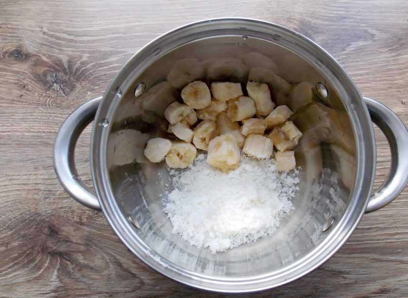 1. Этап. Кокосовый смузи: В глубокую миску, у меня литровая кастрюлька, выложите измельченный кокос. Банан вымойте, очистите, порежьте на кусочки и добавьте к кокосу.