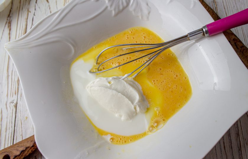 1. Этап. Миндальный пирог со сливами: К яйцам влейте йогурт и добавьте сметану, перемешайте.