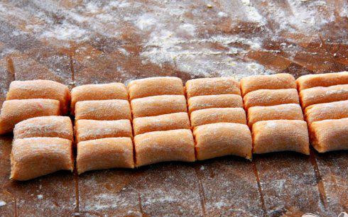 1. Этап. Ньокки из сладкого картофеля с сырным соусом: 4. Выложить тесто на посыпанную мукой поверхность, разделить на 3 равные части. Раскатать между ладонями, формируя из теста длинные веревки около 50 см в длину и 2,5 см в диаметре. Разрезать каждую веревку на 20 штук.