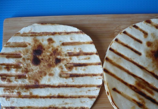 1. Этап. Закуска с тунцом на лепешке: Разогрейте сковороду гриль на умеренно сильном огне. Смажьте одну сторону лепешек оставшимся оливковым маслом, положите смазанной стороной на сковороду и обжарьте до появления характерных черных отметин в местах соприкосновения, примерно 1 минуту.