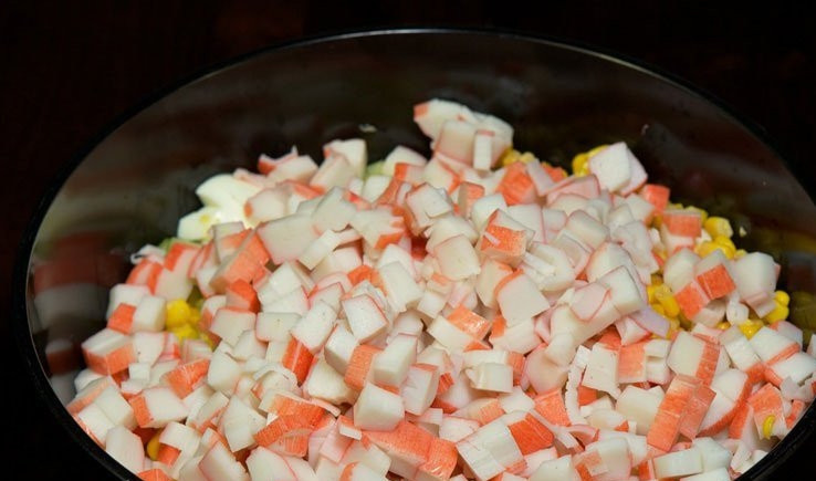 1. Этап. Крабовый салат: Далее внесите нарезанные крабовые палочки и кукурузу.