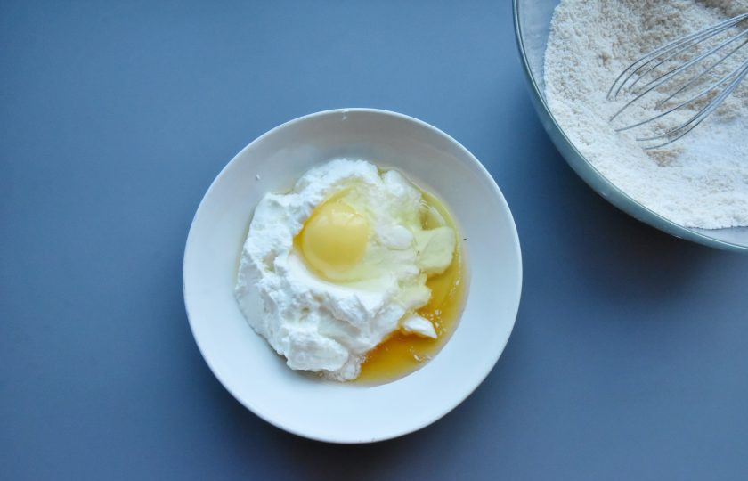 1. Этап. ПП капкейки: В отдельной емкости соедините мягкий творог, яйцо, сироп топинамбура. Растопите кокосовое масло в микроволновой печи в течение 30 секунд, остудите и добавьте к жидким составляющим теста. Размешайте смесь венчиком до объединения всех компонентов в однородную смесь.