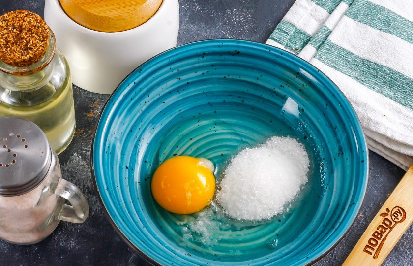 1. Этап. Жареные яблочные кольца: Куриное яйцо вбейте в глубокую емкость, влейте теплую воду, всыпьте соль и сахар. Взбейте все вместе примерно 1-2 минуты.