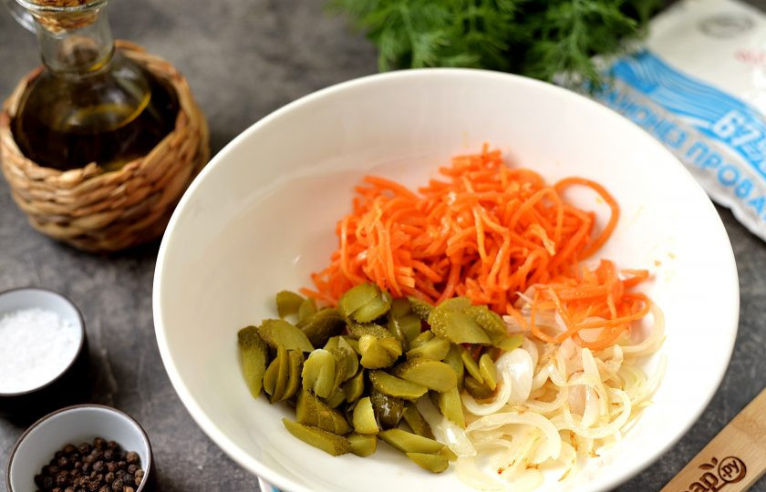 1. Этап. Салат из куриной печени с морковью по-корейски: Нарежьте огурцы тонкими ломтиками, слегка измельчите морковь по-корейски, переложите в глубокую миску, добавьте обжаренный и остывший лук.