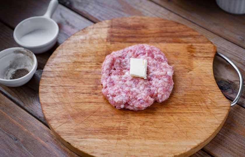 1. Этап. Котлеты Праздничные: Затем увлажненными руками отделяйте небольшую часть фарша, сформируйте из нее лепешку, на центр этой лепешки выложите кубик сливочного масла с размером стороны примерно в 1.5 см.