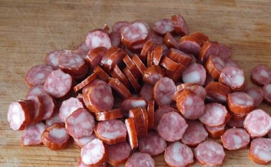 1. Этап. Тушеная капуста с колбасками: Колбаски нарезаем кружочками. Добавляем к луку и обжариваем минуты 2-3.