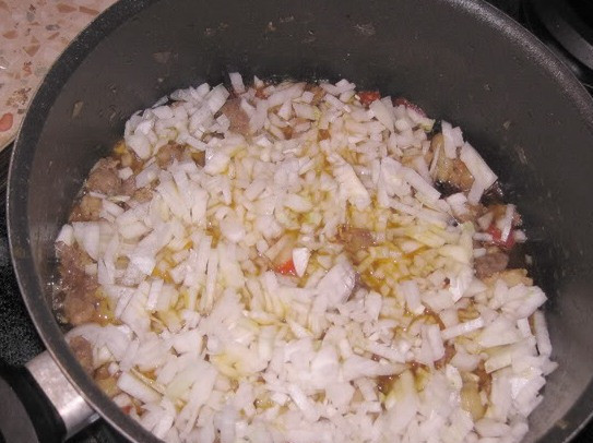 1. Этап. Плов из баранины с помидорами: Оставшийся репчатый лук нарезаем на небольшие кубики и также выкладываем его в кастрюлю, перемешивать ничего не надо.