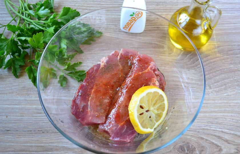 1. Этап. Мясо жареное крупным куском: Мясо разрежьте на порционные куски толщиной примерно 1,5-2 см. Выложите их в глубокую миску, в которую также добавьте растительное масло, соль, перец и паприку, выдавите сок половины лимона, хорошенько все перемешайте. Миску затяните пищевой пленкой и отправьте в холодильник минимум на 1 час, а лучше на 3-4 часа.