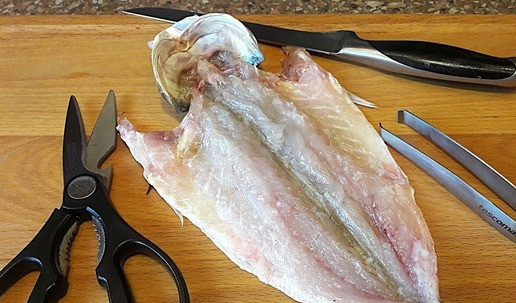 1. Этап. Сочный сибас, запеченный с овощами: Рыбку очистить от чешуи. Ополоснуть. Разрезать по брюшку. Выпотрошить. Удалить жабры, хребет и реберные косточки.