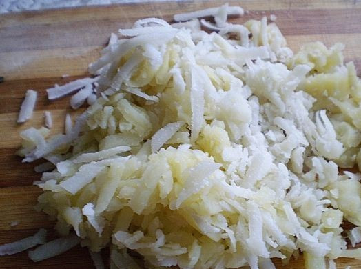 1. Этап. Слоеный салат с ветчиной: Картофель отвариваем и остужаем. Очищаем от кожуры и натираем на крупной терке. Выкладываем на плоское блюдо первым слоем. Солим и смазываем майонезом.