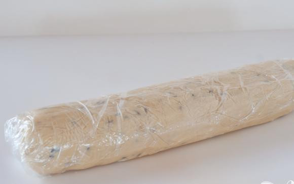 1. Этап. Ванильно-лавандовые коржики: 2. Посыпать руки мукой и выложить тесто на кусок полиэтиленовой пленки. Раскатать в форме бревна длиной около 25 см. Обернуть тесто полиэтиленом и поставить в морозильную камеру на 30 минут или в холодильник как минимум на 1 час.