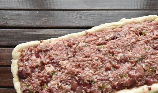 1. Этап. Страсбурский пирог: Начинаем собирать пирог. Фому, для надежности выстелите пергаментом. Достаньте из холодильника тесто. Разделите тесто на 2 неравные части. Большую часть раскатайте в пласт и оформите дно и бока формы оставляя небольшие свободные края для скрепления швов. На дно формы выложите половину начинки 2 из красного мяса, сделав по центру углубление для рулета. Выложите по центру рулет из белого мяса с грибной начинкой и печенью. Сверху распределите оставшуюся начинку 2.