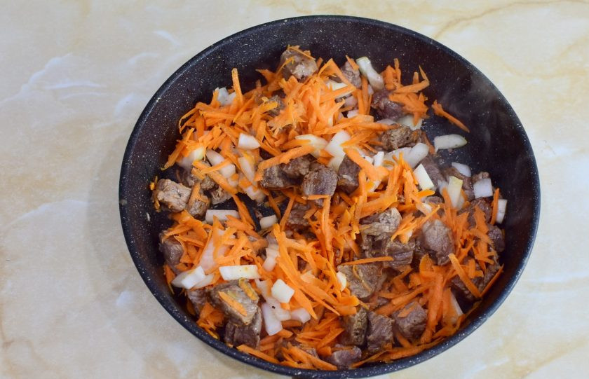 1. Этап. Лосятина с киви: Очистите лук и морковь. Измельчите любым удобным способом и выложите в сковороду к мясу. Обжарьте все вместе еще 3-5 минут.