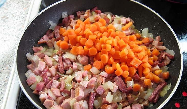 1. Этап. Солянка с маслинами: Очищаем лук и морковь, мелко их нарезаем. Колбасу также нарежем небольшими кусочками. Обжариваем всё на растительном масле, до золотистого цвета.