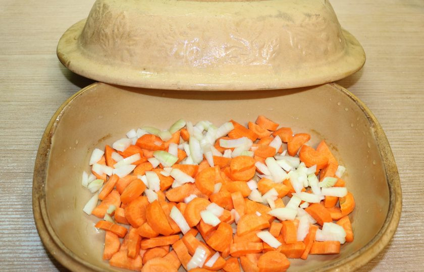 1. Этап. Фасоль с колбасками: В казан или специальную форму для запекания с крышкой налейте капельку масла, выложите лук и морковь.