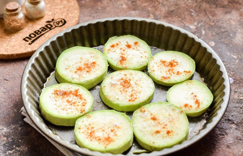 1. Этап. Кабачки под шубой в духовке: Посыпьте кабачки солью, перцем по вкусу, также можете добавить паприку и специи на свое усмотрение.