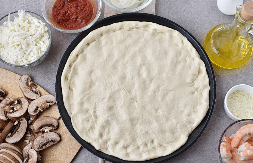 1. Этап. Пицца с креветками и грибами: Включите духовку разогреться до 250-260 градусов. Подошедшее тесто обомните и уложите руками в форму для выпечки пиццы.