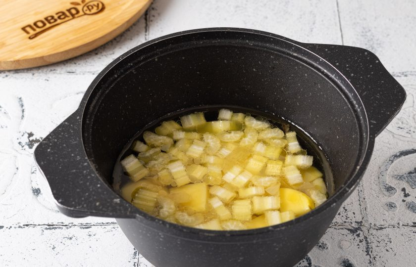 1. Этап. Чесночный суп: Добавьте нарезанный сельдерей, соль и черный молотый перец. Влейте воду. Доведите до кипения и варите до мягкости картофеля около 15-18 минут.