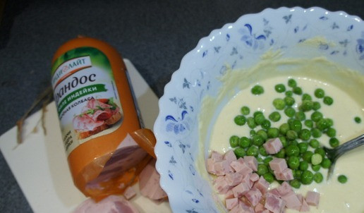 1. Этап. Кукурузные кексы «Школьные»: Зелёный горошек высыпьте в тесто, можно не размораживать. Три кружка колбасы нарежьте кубиком размером с горошек. Добавьте в тесто. Посолите по вкусу. Добавьте немного тёртого сыра и зелени.