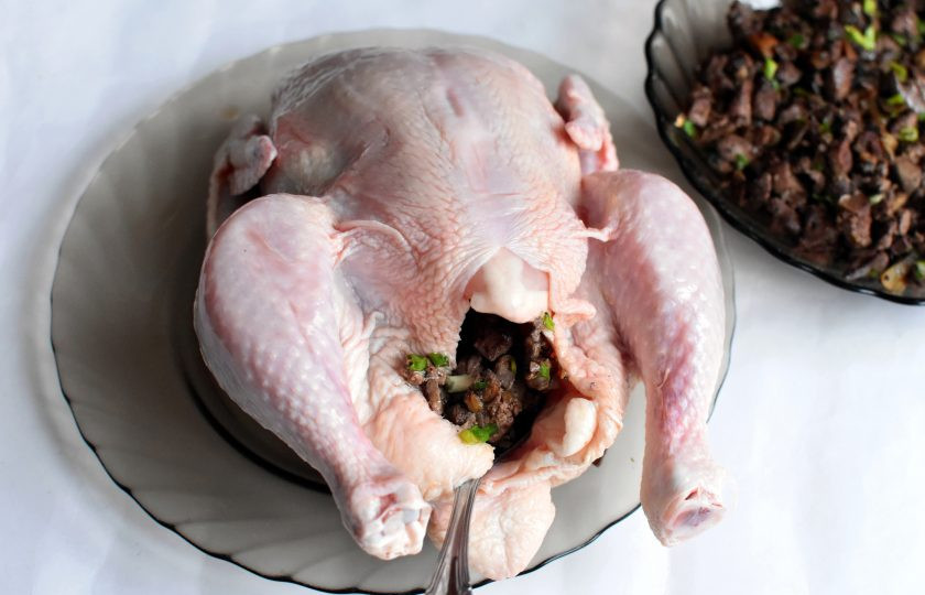 1. Этап. Курица, фаршированная печенью: Курицу промойте, хорошо обсушите и натрите солью снаружи и внутри. Размягченное сливочное масло распределите под кожей грудки. Нафаршируйте курицу начинкой, не набивая слишком плотно. Заколите отверстие зубочистками, свяжите ножки и подверните крылья к спинке.