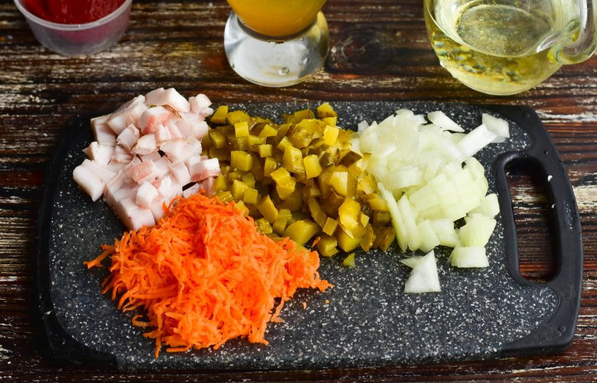 1. Этап. Рассольник по-россошански: Нарежьте кубиками сало, лук, огурец. На терке натрите морковь.