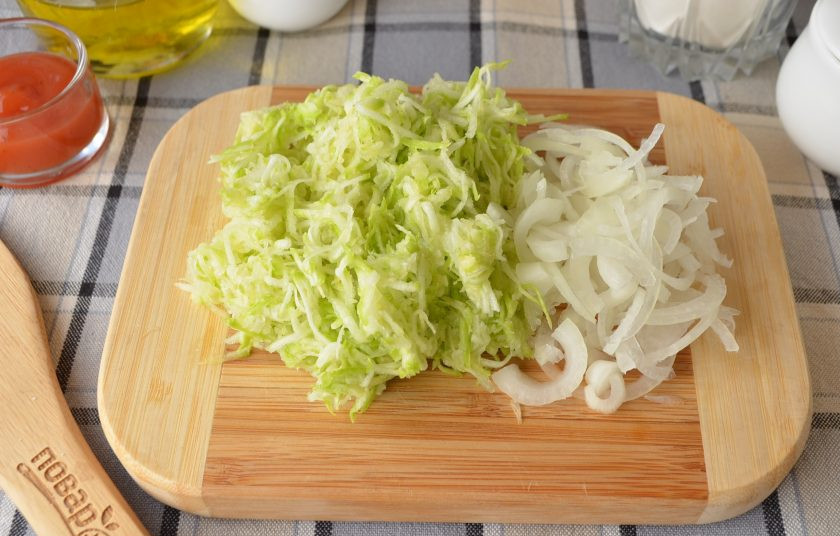 1. Этап. Кабачковый хлеб в домашних условиях: Лук очистите и порежьте максимально тонко. Кабачок натрите на терке и отожмите от сока.