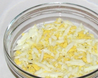 1. Этап. Салат с рыбной консервой: Вареные яйца очистим и натрем на крупной терке. Выкладываем на грибы половину количества яиц. Слегка смазываем майонезом.