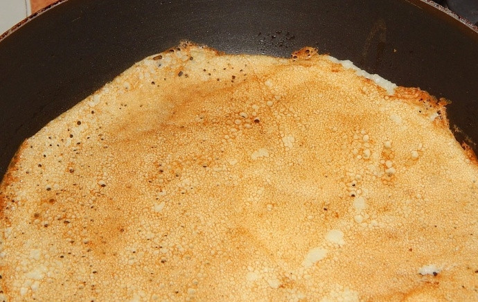 1. Этап. Вкусные блины на воде: Когда блин зарумянится с одной стороны, подденьте его аккуратно лопаткой и переверните на другую сторону.