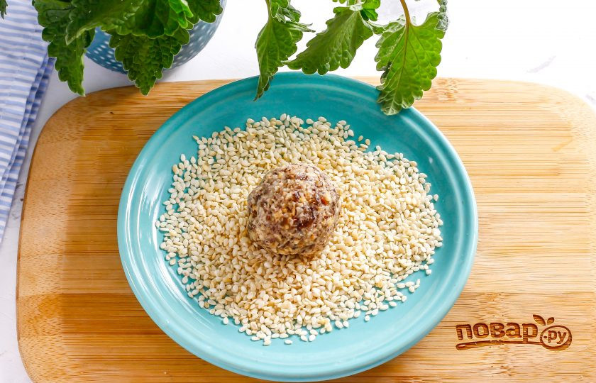 1. Этап. Постные конфеты: Высыпьте на блюдце или тарелку семена кунжута. Обмакните руки в воде и сформируйте небольшие шарики из приготовленной массы. Обпанируйте их в семенах кунжута.