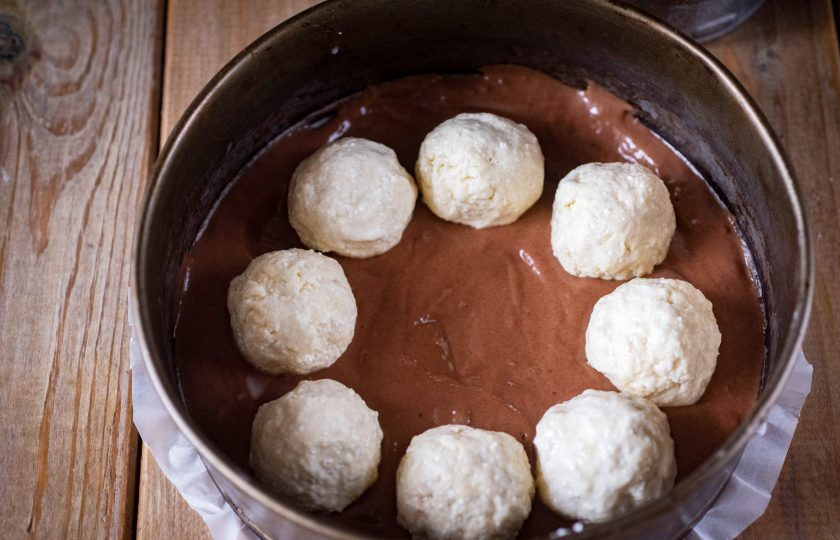 1. Этап. Пирог на кефире с творогом: Форму для выпекания застелите пергаментом для выпечки. Выложите в подготовленную форму половину теста, разровняйте. Из творожной массы скатайте шарики примерно одинакового размера и разложите по тесту, как на фото.