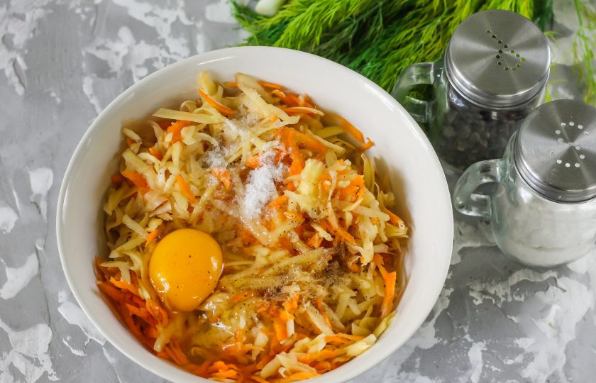 1. Этап. Картофельные драники с морковью: Очистите овощи и натрите их на терке с крупными ячейками. По желанию можно использовать и терку с мелкими ячейками, правда консистенция теста тогда будет чуть менее плотной. Вбейте в овощную массу куриное яйцо, посолите и поперчите. Тщательно вымешайте и добавьте пшеничную муку. Еще раз перемешайте.