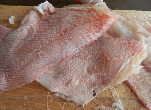 1. Этап. Филе красного окуня в духовке: Рыбу почистите, удалите плавники и очистите от чешуи. Совет: обмотайте доску пищевой пленкой, тогда она не пропитается запахом рыбы. Филе отделите от хребта, пинцетом удалите кости. Кстати, из костей и хребта можно сварить отличный рыбный суп.