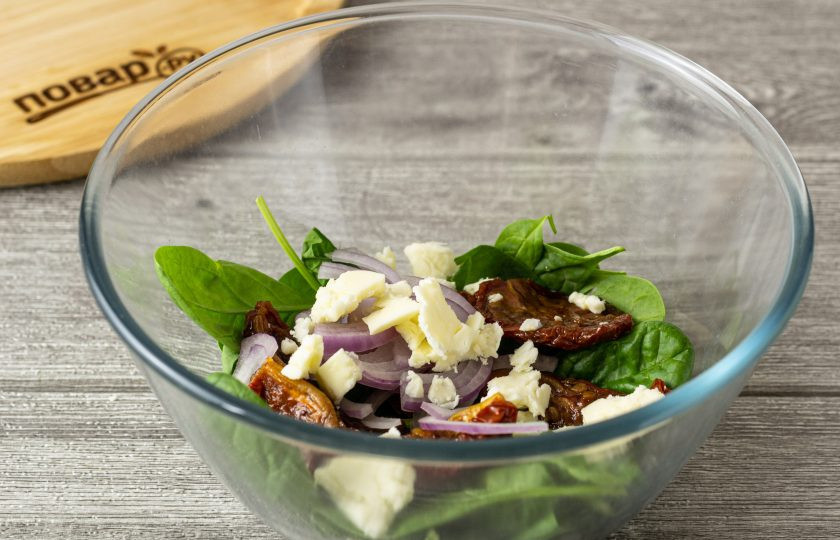 1. Этап. Салат с вялеными томатами: Добавьте вяленые томаты, сыр и красный лук. Заправьте салат, посолите и поперчите по вкусу. Аккуратно перемешайте.