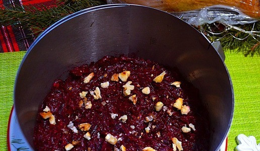 1. Этап. Слоёный салат Рождественское небо: Сервировочное кольцо (16 см.) поставить на блюдо для подачи, насыпать немного мелких сухарей ( они не дадут салату потечь), выложить в него 2/3 свёклы, уплотнить, посыпать орехами.