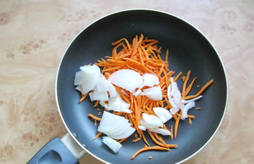 1. Этап. Салат с курицей и лапшой из омлета: Небольшую луковицу очистите, помойте и нарежьте. Добавьте к моркови на сковороду. Налейте подсолнечное масло.