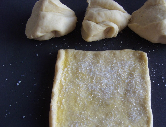 1. Этап. Булочки-сердечки с сахаром: Перед тем как начать делать будущие булочки, ещё разок вымесим тесто. Затем разделим его на небольшие части (у меня получилось 8), раскатываем. Смазываем каждую часть растопленным сливочным маслом и посыпаем сахаром.