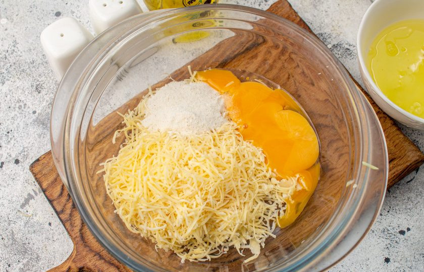 1. Этап. Суфле из кабачков в мультиварке: Тем временем сыр натрите на мелкой терке, выложите в миску. Яйца разделите на желтки и белки. Белки отложите, а желтки добавьте к сыру. Всыпьте манную крупу.
