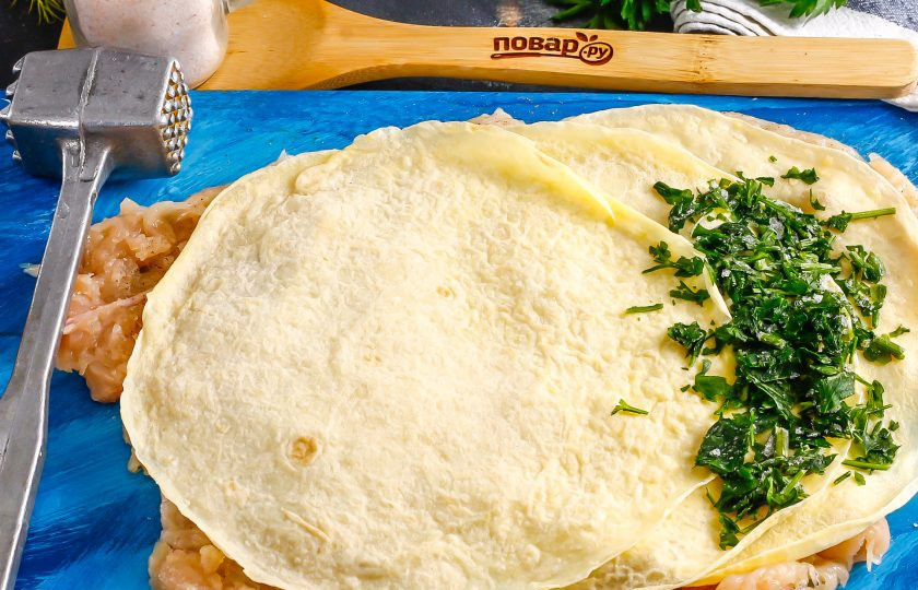 1. Этап. Куриный рулет с блинами: Выложите три блина на рулет. Измельчите промытую зелень и выложите нарезку на край блинов.