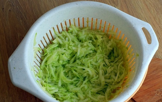 1. Этап. Оладьи из кабачков на сковороде: Кабачок при необходимости очистите и удалите жесткие семена. Молодой кабачок очищать не требуется. Натрите овощ на крупной терке, отожмите лишнюю влагу.