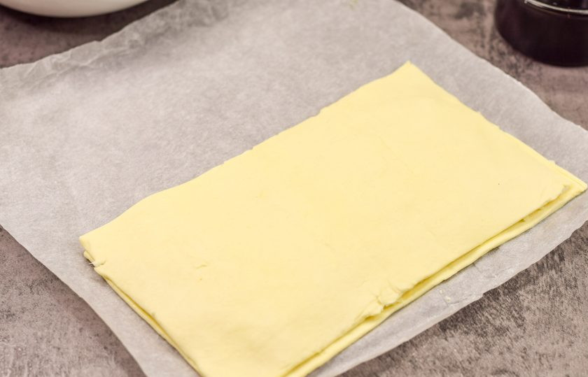 1. Этап. Слоеные палочки с сыром и беконом: Прикройте сыр второй половиной теста и немного раскатайте скалкой, чтобы слои соединились между собой и сыр не выпадал в процессе формирования заготовок.