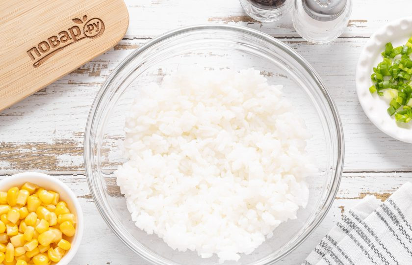 1. Этап. Салат с рисом, кукурузой и майонезом: Рис тщательно промойте до прозрачности. Переложите в кастрюлю с толстым дном, влейте воду в пропорции риса с водой 1:2. Доведите до кипения, слегка подсолите. Варите рис на медленном огне до готовности, под закрытой крышкой. У меня сорт, который варится 25-30 минут, для обычного риса потребуется минут 20. После промойте рис кипятком и откиньте на сито — так он точно не будет слипаться в салате. Переложите рис в глубокую миску.
