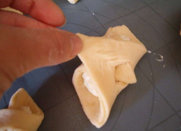 1. Этап. Плюшки с творогом: Заворачиваем тесто, протаскивая один конец в дырочку.