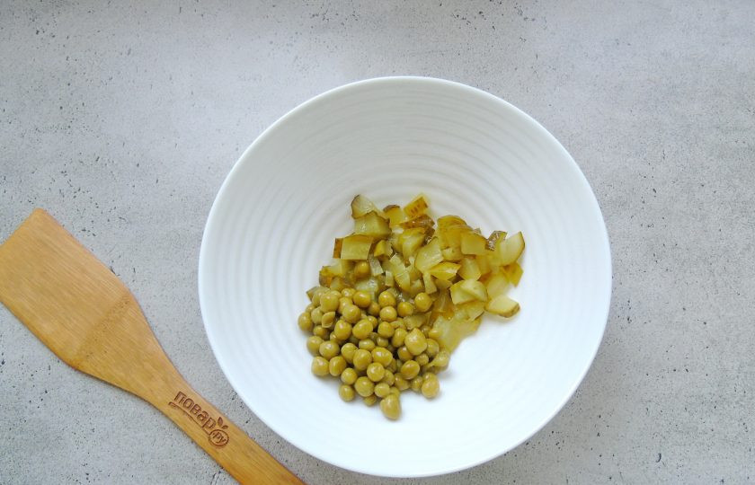 1. Этап. Салат Лада: Консервированный зеленый горошек выложите в салатник. Добавьте нарезанный соленый или маринованный огурец.