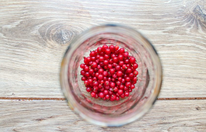 1. Этап. Компот из крыжовника и красной смородины на зиму: Ягоды смородины переберите, удалите веточки и мятые ягоды. Смородину сполосните, дайте воде полностью стечь и выложите в банку.