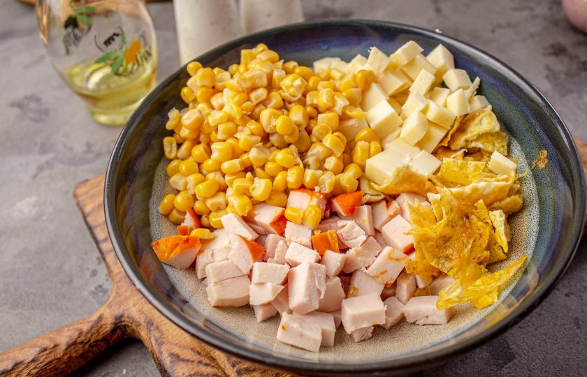 1. Этап. Салат с яичными блинчиками, копчёной курицей и кукурузой: В салатник добавьте консервированную кукурузу без жидкости.
