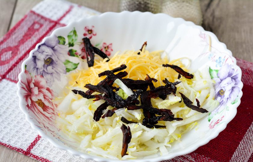 1. Этап. Салат с кукурузой и черносливом: Смешайте капусту, сыр и нарезанный полосками чернослив.