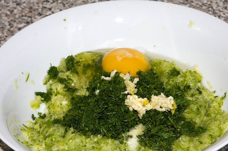 1. Этап. Котлеты из цукини: Слейте образовавшуюся жидкость, добавьте мелко порубленный укроп, измельченный чеснок и яйцо.