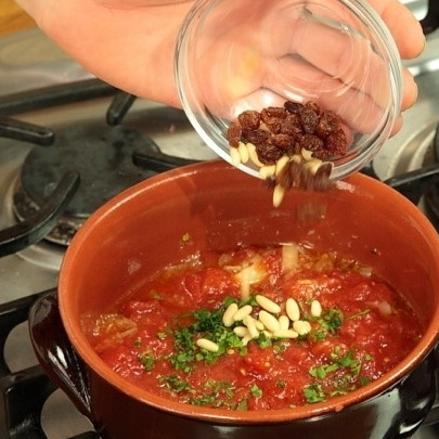 1. Этап. Тушеные кальмары в соусе: В кастрюле разогрейте оливковое масло, обжарьте слегка мелко нарезанные лук и чеснок. Затем добавьте мелко нарезанные помидоры, петрушку и орешки (по желанию). Потушите 10 минут.