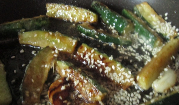 1. Этап. Жареные огурцы от Пугачевой: 3. По прошествии двадцати секунд добавьте огурцы, не переставая мешать, в сковороду насыпьте кунжут. Я также добавляю немного мелко нарезанного болгарского перца.